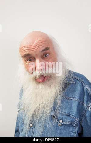 Portrait of senior man sticking out tongue sur fond gris Banque D'Images