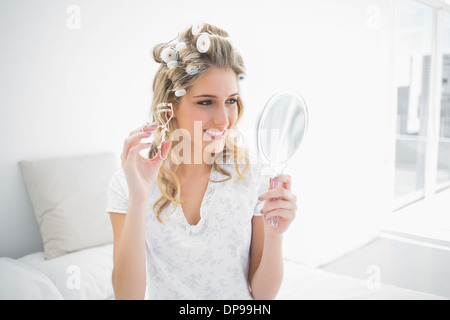 Cheerful blonde holding eyelash curler Banque D'Images