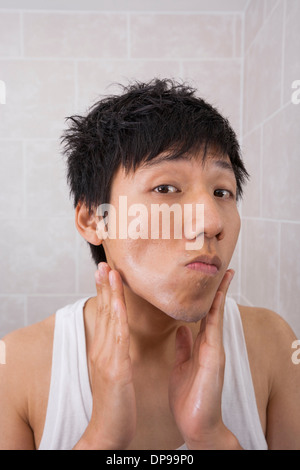 Portrait of mid adult man applying lotion après-rasage dans la salle de bains Banque D'Images