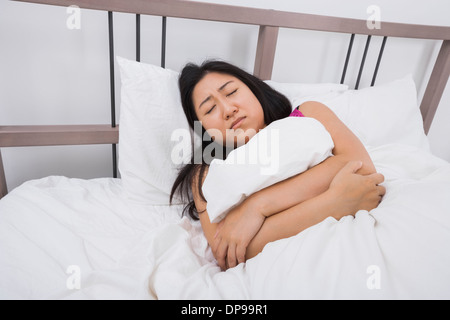 Jeune femme souffrant de maux d'estomac au lit Banque D'Images