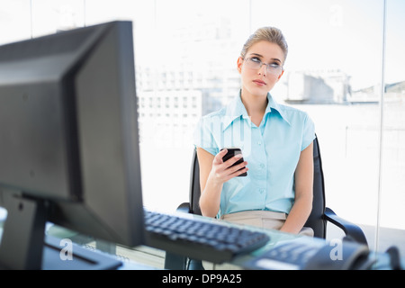 Pensive businesswoman wearing glasses text messaging Banque D'Images