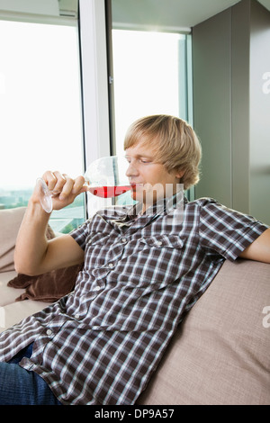 Vue latérale du mid-adult man boire du vin dans la salle de séjour à la maison Banque D'Images