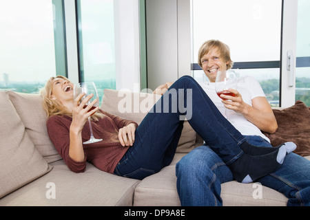 Cheerful couple détendue avec des verres à vin dans la salle de séjour à la maison Banque D'Images