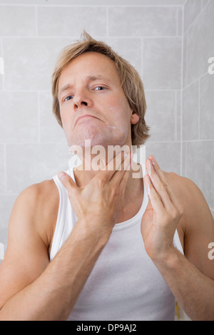 Portrait of mid-adult man applying lotion après-rasage crème hydratante dans la salle de bains Banque D'Images