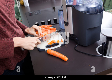 Midsection of woman chopping carrots on cutting board in kitchen Banque D'Images