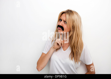 Portrait de confus en fake moustache against white background Banque D'Images