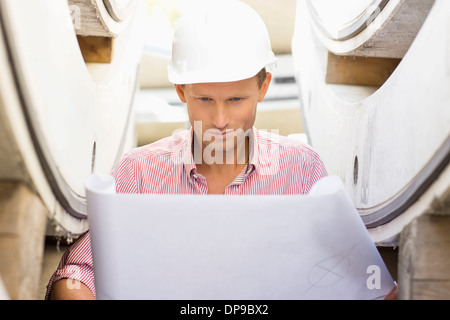 Architect reviewing blueprint at construction site Banque D'Images