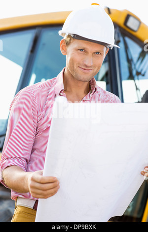 Portrait of male architect holding blueprint at construction site Banque D'Images