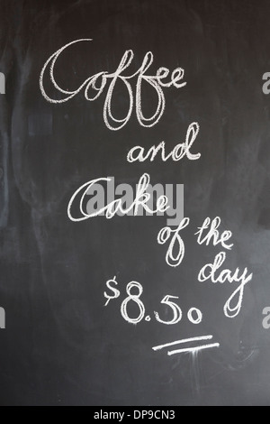 Café et gâteau du jour signe sur un tableau noir dans cafe Banque D'Images