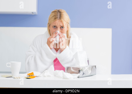 Portrait of young woman blowing nose dans du papier de soie Banque D'Images