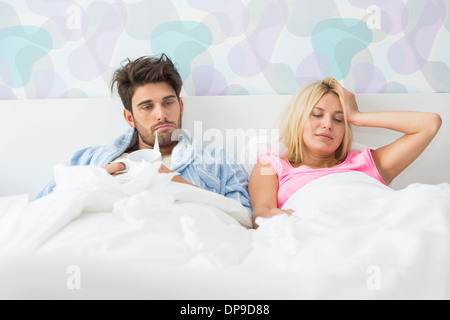 Malades frustrés couple lying in bed at home Banque D'Images