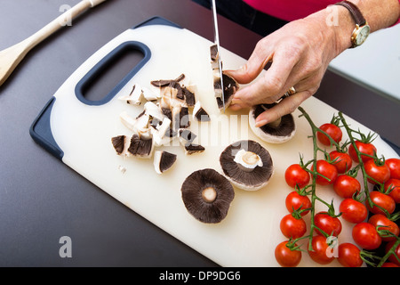 Woman's hand Hacher les champignons sur une planche à découper Banque D'Images