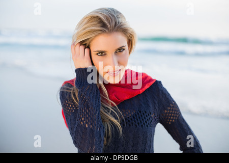 Cheerful gorgeous blonde courir sa main dans ses cheveux Banque D'Images