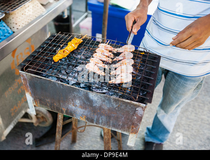 La section basse du jeune homme la cuisson sur barbecue crevettes Koh Pha Ngan, Thailand Banque D'Images