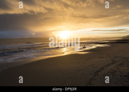 Surfeur debout sur le rivage avec sa planche de surf qui donne sur la mer sur la plage de Boscombe à Dorset, Angleterre, Royaume-Uni Banque D'Images