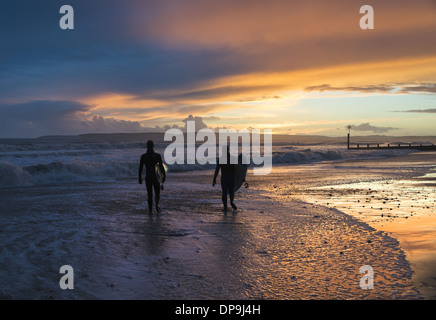 Balades le long du littoral des surfeurs au coucher du soleil sur la plage de Boscombe dans le Dorset, Angleterre, RU Banque D'Images