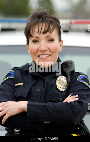 Une ambiance conviviale et smiling Hispanic femme officier avec sa voiture de patrouille. Banque D'Images