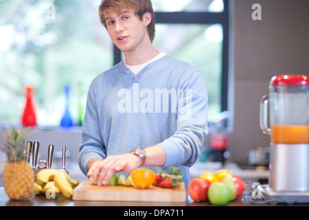 Jeune homme dans la cuisine préparer des boissons de fruits Banque D'Images