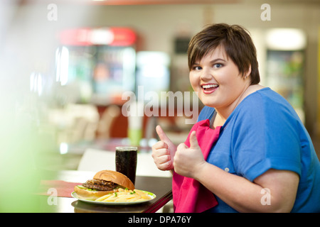 Young woman in cafe avec repas malsains Banque D'Images