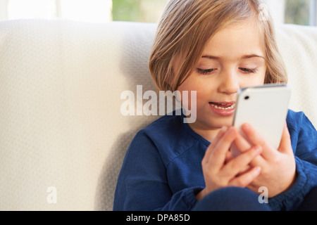 Girl on sofa using smartphone Banque D'Images