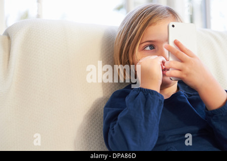 Girl on sofa using smartphone Banque D'Images