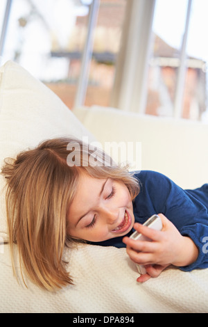 Girl on sofa using smartphone Banque D'Images