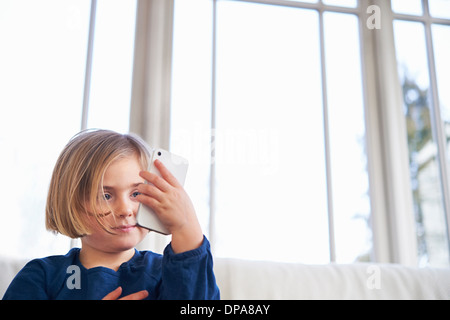 Girl on sofa using smartphone Banque D'Images