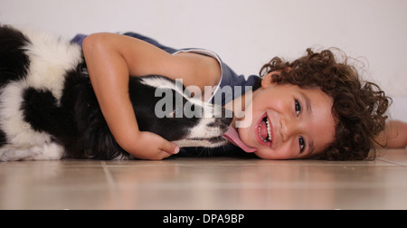 Young boy lying on floor serrant son chien de compagnie