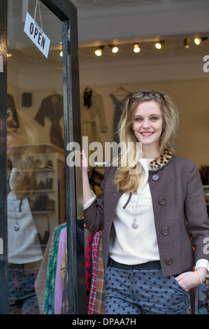 Woman standing in doorway of clothes shop Banque D'Images