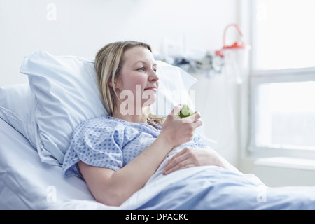 Patient lying in hospital bed eating apple Banque D'Images