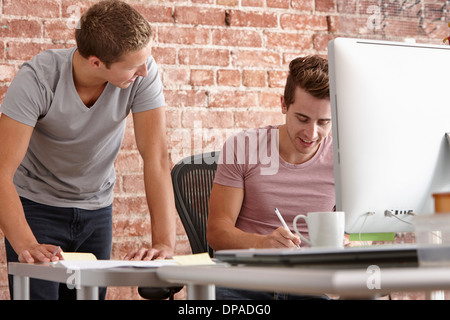 Les jeunes hommes parlant au bureau avec ordinateur Banque D'Images