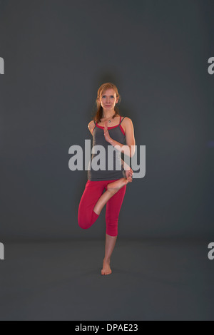 Woman in yoga pose sur fond gris Banque D'Images