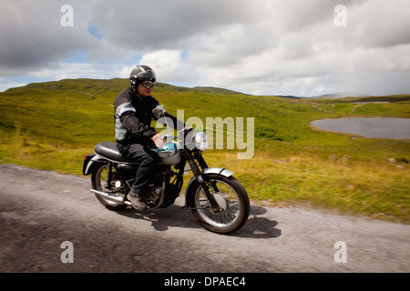 Senior male sur moto on rural road Banque D'Images