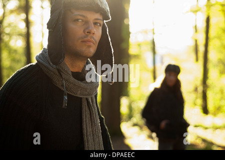 Portrait of mid adult man wearing hat and scarf, woman in background Banque D'Images