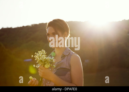 Jeune femme en prairie avec bouquet de fleurs sauvages