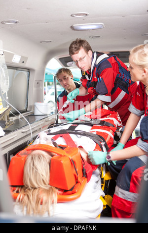 Les ambulanciers avec goutte-à-goutte intraveineux et patient en ambulance Banque D'Images