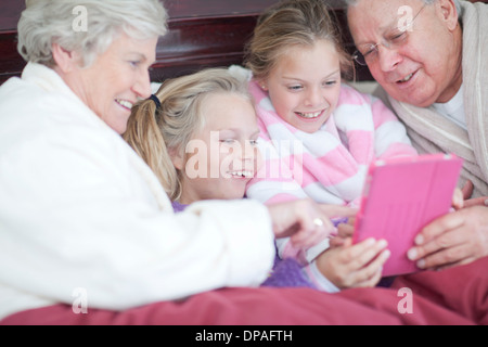 Les grands-parents et petits-enfants de jouer jeu numérique au lit Banque D'Images