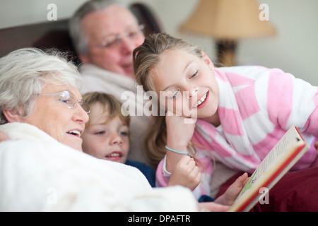 Les grands-parents et petits-enfants la lecture de contes au lit Banque D'Images