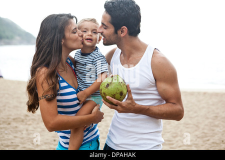Family on beach, mother kissing son on joue