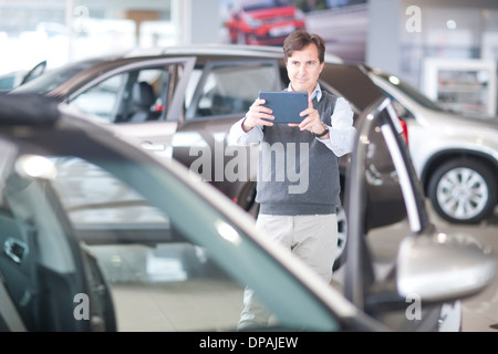 Mid adult man photographing car in showroom Banque D'Images