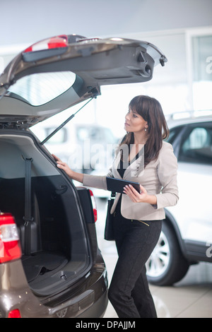 Mid adult woman checking car boot in showroom Banque D'Images