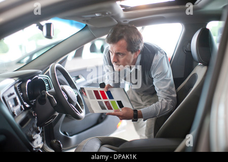 Mid adult man avec un échantillon de couleur dans la salle d'exposition de voiture Banque D'Images