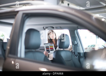 Mid adult woman with color swatch en car showroom Banque D'Images