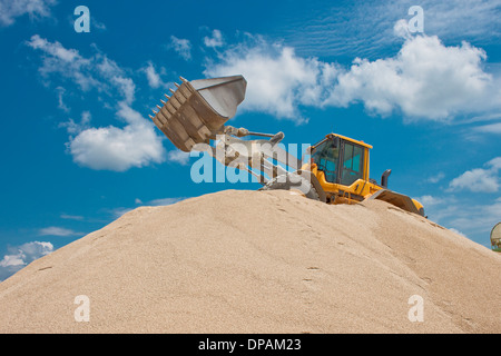 Excavatrice jaune sur un site de construction contre le ciel bleu Banque D'Images