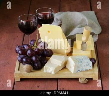 Assortiment de fromages servis sur une planche en bois avec des raisins Banque D'Images