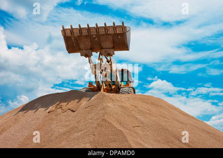 Excavatrice jaune sur un site de construction contre le ciel bleu Banque D'Images