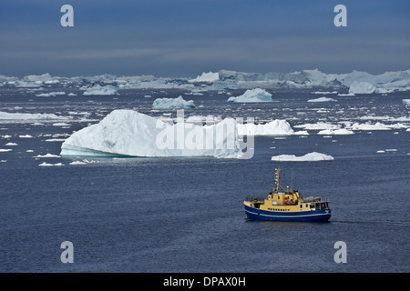 Bateau de pêche entre les icebergs dans la baie de Disko, Ilulissat, Groenland Ouest Banque D'Images