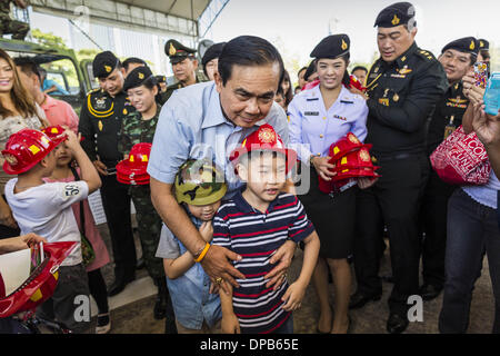 Bangkok, Thaïlande. Jan 11, 2014. Général PRAYUTH CHAN-OCHA, commender en chef de l'Armée royale thaïlandaise, donner aux enfants casques jouet pendant une journée des enfants juste à Bangkok. L'Armée royale thaïlandaise a organisé une journée des enfants ''événement'' à la 2e Division de cavalerie de la Garde du roi à Bangkok. Les enfants ont la possibilité d'examiner les armes militaires, grimper sur des chars, pièces d'artillerie et d'hélicoptères et d'examiner les installations médicales de bataille. La Journée des enfants vient juste au milieu des conflits politiques et des préoccupations d'un possible coup d'État en Thaïlande. Credit : ZUMA Press, Inc./Alamy Live News Banque D'Images