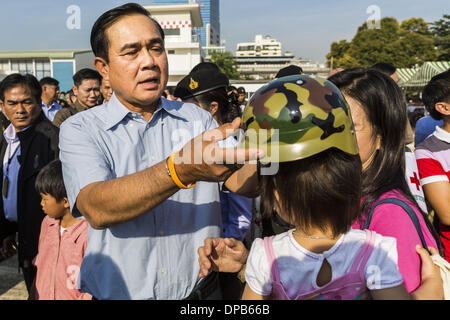 Bangkok, Thaïlande. Jan 11, 2014. Général PRAYUTH CHAN-OCHA, commender en chef de l'Armée royale thaïlandaise, donner aux enfants casques jouet pendant une journée des enfants juste à Bangkok. L'Armée royale thaïlandaise a organisé une journée des enfants ''événement'' à la 2e Division de cavalerie de la Garde du roi à Bangkok. Les enfants ont la possibilité d'examiner les armes militaires, grimper sur des chars, pièces d'artillerie et d'hélicoptères et d'examiner les installations médicales de bataille. La Journée des enfants vient juste au milieu des conflits politiques et des préoccupations d'un possible coup d'État en Thaïlande. Credit : ZUMA Press, Inc./Alamy Live News Banque D'Images