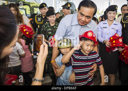 Bangkok, Thaïlande. Jan 11, 2014. Général PRAYUTH CHAN-OCHA, commender en chef de l'Armée royale thaïlandaise, donner aux enfants casques jouet pendant une journée des enfants juste à Bangkok. L'Armée royale thaïlandaise a organisé une journée des enfants ''événement'' à la 2e Division de cavalerie de la Garde du roi à Bangkok. Les enfants ont la possibilité d'examiner les armes militaires, grimper sur des chars, pièces d'artillerie et d'hélicoptères et d'examiner les installations médicales de bataille. La Journée des enfants vient juste au milieu des conflits politiques et des préoccupations d'un possible coup d'État en Thaïlande. Credit : ZUMA Press, Inc./Alamy Live News Banque D'Images